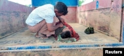 FILE - A man looks at the body of a child at a local school that was hit by an air attack carried out by the Myanmar military against the People Defense Force, in Sagaing, Myanmar, Sept. 16, 2022 in this social media video.