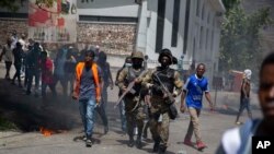 La policía camina entre los manifestantes durante una protesta en la cpaital, Puerto Príncipe, tras el asesinato del presidente de Haití, ocurrido el miércoles 7 de julio de 2021