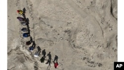 An aerial view shows a research team standing alongside the fossil footprint trackway at the excavation site on the eastern side of Lake Turkana in northern Kenya, 2022. (Louise Leakey via AP)