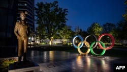 A bronze statue of Pierre de Coubertin (L), founder of the International Olympic Committee and the Olympic Rings are displayed at Japan Sport Olympic Square in Tokyo on April 20, 2020. - A Japanese expert who has criticised the country's response to…