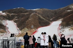 FILE - Journalists stand in front of ski slopes during an organized media tour to the National Alpine Skiing Center, a venue of the 2022 Winter Olympic Games, in Beijing's Yanqing district, China, Feb. 5, 2021.