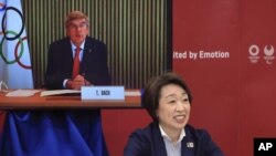 El presidente del COI, Thomas Bach (en la pantalla), interviene en una reunión sobre los Juegos Olímpicos de Tokio 2020, mientras la presidenta del comité organizador, Seiko Hashimoto (en primer plano) escucha sus palabras en Tokio, el 20 de marzo de 2021