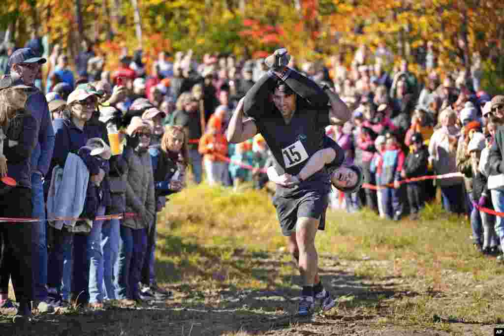 Nic Vinsonhaler carries Tara Rogowski while competing in the North American Wife Carrying Championship, Oct. 12, 2024, at Sunday River ski resort in Newry, Maine. 