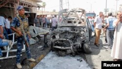 A policeman stands guard at the site of a car bomb attack in Kirkuk, Sept. 19, 2014.