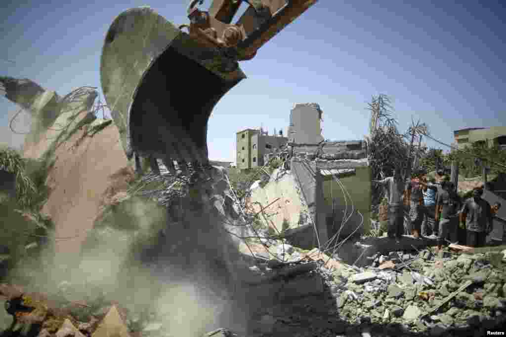 Palestinians gather as  rescue workers search for victims from under the rubble of a house, which witnesses said was destroyed by an Israeli airstrike, in Beit Lahiya, northern Gaza Strip, Aug. 25, 2014.  