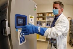 Pharmacy supervisor Kevin Weissman wears a thick glove as he opens the door of a special freezer that will hold the Pfizer vaccine at LAC USC Medical Center, during the outbreak of the coronavirus disease, in Los Angeles, California, Dec. 10. 2020.