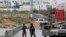 FILE - Israeli soldiers stand guard after the military blocked the road with an earth berm at one of the exits of the West Bank city of Hebron, Nov. 7, 2015.