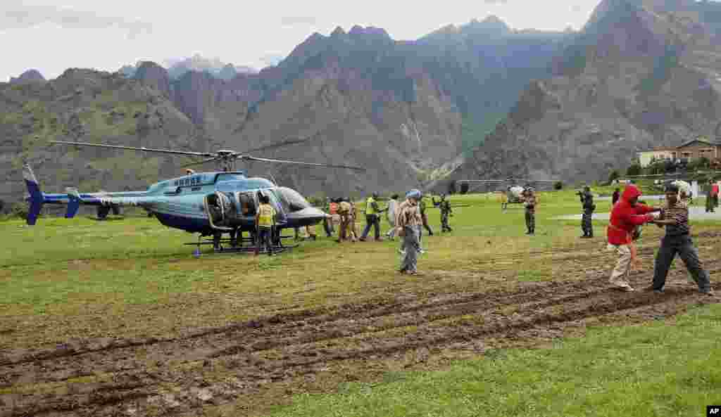 Rescuers help escort stranded pilgrims to helicopters to evacuate at Joshimath in the northern Indian state of Uttarakhand, India, June 19, 2013. 