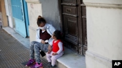 Una mujer y un niño sentados en la entrada de una casa en Buenos Aires, Argentina, el 16 de mayo de 2020.