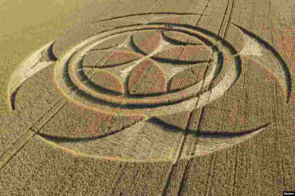 Visitors stand inside a crop circle in a wheat field, which was discovered by a local farmer, according to local media, close to the Canadian National Vimy Memorial in Vimy, France, July 11, 2020.