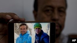 FILE - Karrar Haidri, secretary of the Alpine Club of Pakistan, shows pictures of two missing climbers, Briton Tom Ballard, right, and Italian Daniele Nardi in Islamabad, Pakistan, March 4, 2019.