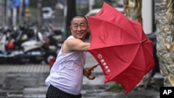 In this photo released by Xinhua News Agency, a man holding an umbrella struggles against the wind following the landfall of typhoon Yagi in Haikou, south China's Hainan Province, Sept. 6, 2024. 