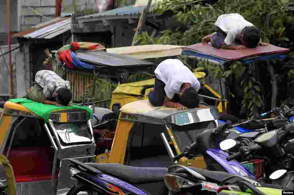 Youths praying atop motorcycle taxis in front of Al-Satie Mosque in Baseco, Tondo city, metro Manila, July 4, 2014.