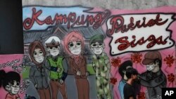 Seorang warga mengenakan masker, berjalan melewati mural di kawasan Rawa Pasung, Bekasi, 23 Juli 2020.