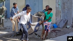 Somalis carry away the body of a dead civilian after a bomb attack on Ambassador Hotel in Mogadishu, Somalia Thursday, June 2, 2016. Somalia's Islamic extremist rebels, al-Shabab, stormed the hotel, often frequented by government officials and business executives, killing people and taking a number of hostages, police said. (AP Photo/Farah Abdi Warsameh)