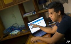 In this Jan. 4, 2015 photo, Rafael Antonio Broche Moreno talks during an interview with The Associated Press, next to his computer, modem and intranet network cabling in Havana. Disconnected from the real Internet, the intranet network is limited.