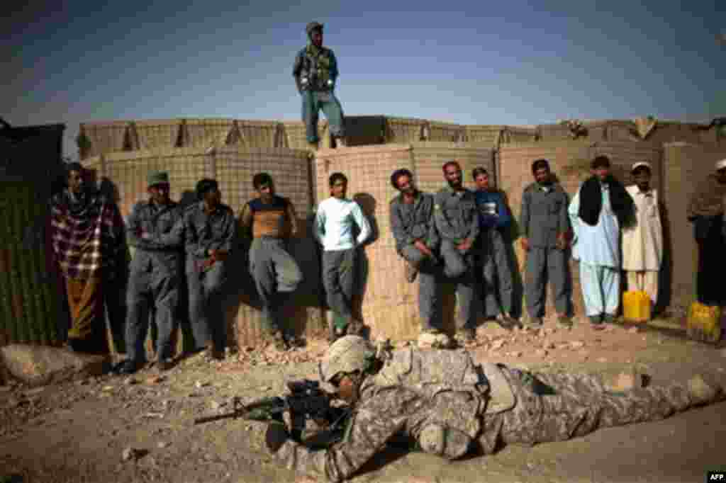 US soldier PFC Mecale Bryant, from Houston, Texas demonstrates firing positions to Afghan policemen on the outskirts of Kandahar City, Afghanistan, Tuesday, Oct. 26, 2010. (AP Photo/Rodrigo Abd)