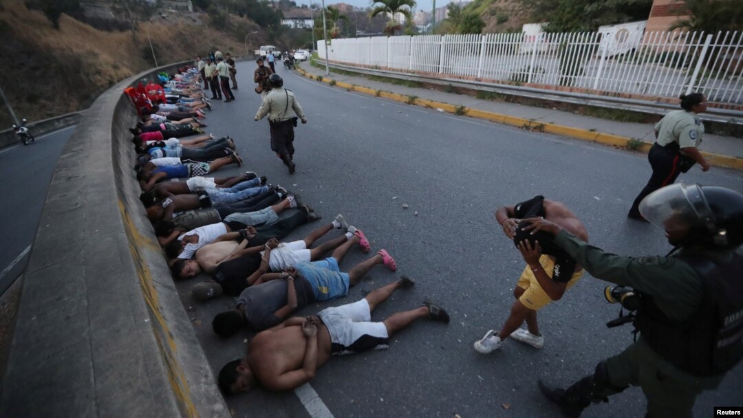 Orang-orang ditahan pasukan keamanan berbaring di jalanan setelah penjarahan merajalela di tengah pemadaman listrik yang meluas di Caracas, Venezuela, 10 Maret 2019 (foto: Reuters/Ivan Alvarado)