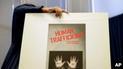 A city employee sets up a display board in preparation for a news conference to announce the results of a task force's eight-month effort to target sex traffickers in the Long Beach area, Sept. 24, 2014, in Long Beach, Calif. 