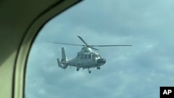 Sebuah helikopter militer China terbang dekat pesawat Biro Perikanan dan Kelautan Filipina (BFAR) atas beting Scarborough Shoal, Laut China Selatan, Selasa, 18 Februari 2025. (Foto: Joeal Calupitan/AP Photo)