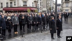 French President Francois Hollande and Paris Mayor Anne Hidalgo stand at attention after unveiling a plaque near the Petit Cambodge and Carillon cafes in Paris, France, during a ceremony held for the victims of last year's attacks, Nov. 13, 2016.