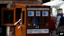 A ticket vendor for a canal boat tour operator waits in his booth in Bruges, Belgium, Aug. 24, 2020.