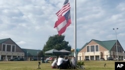 Un grupo de personas se reúne en el asta de la bandera frente a la entrada de la escuela secundaria Apalachee, el jueves 5 de septiembre de 2024 en Winder, Georgia, un día después del tiroteo en la escuela. 