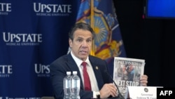 New York state Gov. Andrew Cuomo holds a copy of the New York Daily News as he speaks during his daily coronavirus news briefing at SUNY Upstate Medical University in Syracuse, New York, April 28, 2020.