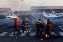 FILE - French fishermen block trucks carrying UK-landed fish to protest for the slow issuance of licenses to fish inside British waters, at the fishing port in Boulogne-sur-Mer, France, Apr. 23, 2021.