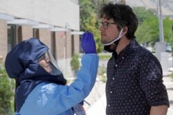 FILE - A Salt Lake County Health Department public health nurse performs a coronavirus test outside the Salt Lake County Health Department in Salt Lake City, Utah, July 10, 2020.