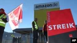 Pegawai ritel online Amerika Amazon protes selama mogok kerja di depan salah satu pusat logistik di Graben, Jerman.