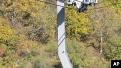 Armenian President Serzh Sarkisian (C) and the head of the Armenian Apostolic Church, Karekin II (L) ride in a cable car at the newly opened cable line near Tatev monastery in Armenia's southern mountains close the border with Iran, 16 Oct 2010