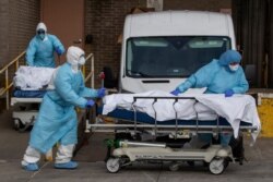 Medical personnel wearing personal protective equipment remove bodies from the Wyckoff Heights Medical Center, April 2, 2020 in the Brooklyn borough of New York.