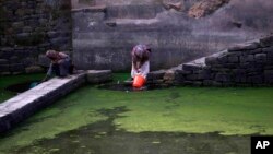 Women collect water from a rain-water pond on the outskirts of Sana'a, Yemen, May 8, 2013. 