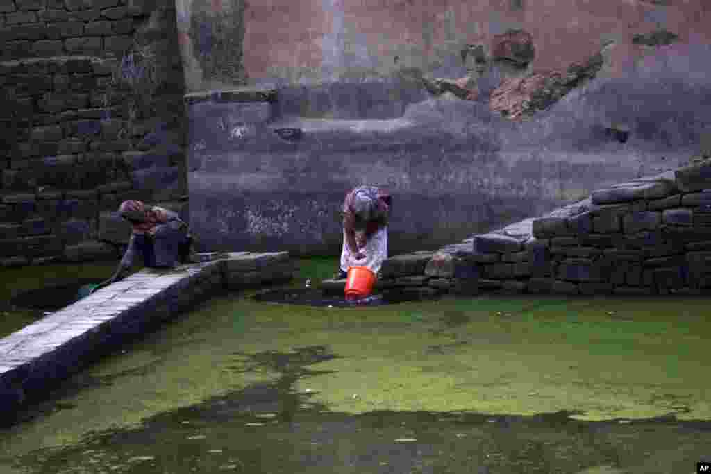 Dua orang perempuan mengambil air dari sebuah kolam air hujan di pinggiran kota Sana&#39;a, Yaman.