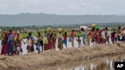 Muslim Rohingya, yang menghabiskan empat hari di tempat terbuka setelah menyeberang dari Myanmar ke Bangladesh, membawa barang-barang mereka setelah diizinkan menuju kamp pengungsian di Palong Khali, Bangladesh, 19 Oktober 2017. (Foto: AP)