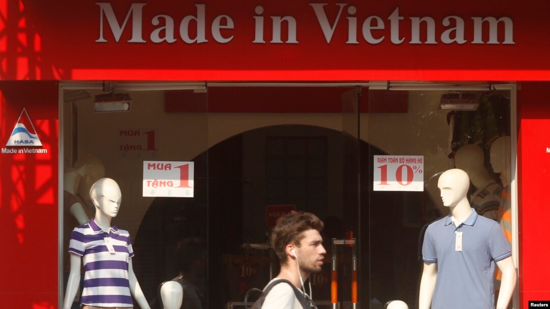 Du khách đi ngang một cửa hàng bán quần áo ở Hà Nội.