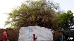 FILE - An internally displaced child stands outside a tent pitched at the Hasahisa secondary school on July 10, 2023, which has been made into a make-shift camp to house those fleeing violence in war-torn Sudan.