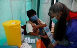 Dr. Jacqueline Marshall talks to patient Margaret Duncan Williams before giving her a dose of the AstraZeneca COVID-19 vaccine during a pop-up vaccination drive in Kilburn, London, Feb. 28, 2021.