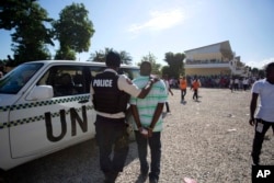 Lapolis arete yon neg yo suspek de frod elektoral nan Potoprens, Ayiti, 25 Oktob 2015.