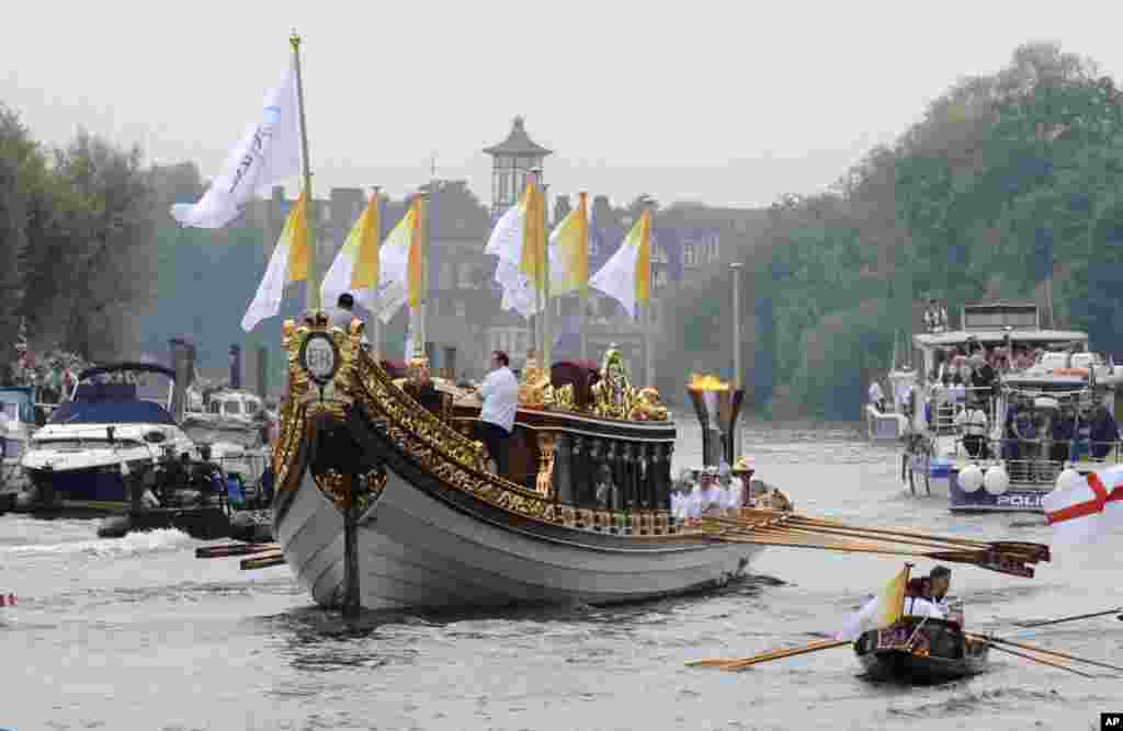 This photo provided by LOCOG shows the royal barge Gloriana carrying Olympic flame burning in the cauldron as it makes its way down the River Thames towards Richmond Bridge during the final day of the Olympic torch relay in London, July 27, 2012.