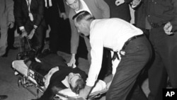 Lee Harvey Oswald, accused assassin of President John F. Kennedy, is placed on a stretcher after being shot in the stomach in Dallas, Texas, November 24, 1963.