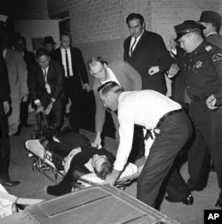 FILE - Lee Harvey Oswald, accused assassin of President John F. Kennedy, is placed on a stretcher after being shot in the stomach in Dallas, Texas, Nov. 24, 1963.