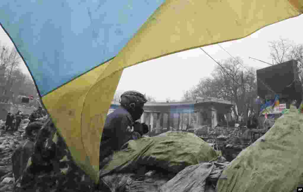 A protester guards a barricade in front of riot police in central Kyiv, Feb. 9, 2014.&nbsp;