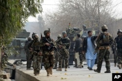 Uniformed and plainclothed Afghan security forces patrol the site of a deadly suicide attack in Jalalabad, Afghanistan, Jan. 24, 2018.