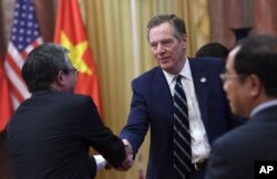 FILE - U.S. Trade Representative Robert Lighthizer, center, shakes hands with Vietnamese Ambassador to the U.S. Pham Quang Vinh as they wait for the welcoming ceremony of U.S. President Donald Trump at the presidential palace in Hanoi, Nov. 12, 2017.