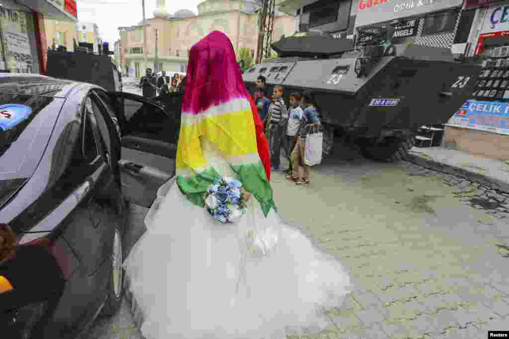The bride Dilges Baskin, her face covered by a scarf with yellow-red-green Kurdish colors, gets in her wedding car in Yuksekova in the Kurdish-dominated southeastern Hakkari province of Turkey, Sept. 6, 2015.