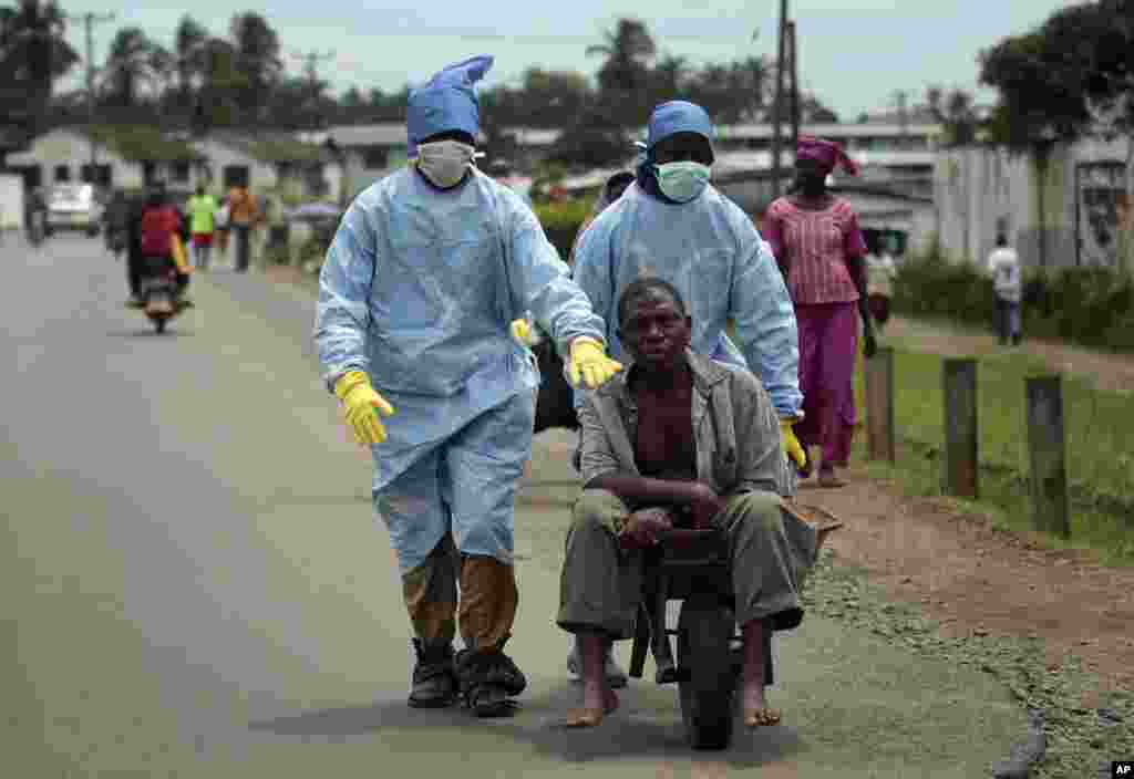 Residents of the St. Paul Bridge neighborhood wearing personal protective equipment take a man suspected of the Ebola virus to the Island Clinic in Monrovia, Liberia.