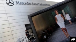 A designer's runway show is shown on a television screen outside the Fashion Week venue at New York's Lincoln Center, Feb. 6, 2013.