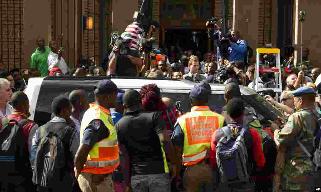 Members of the public crowd around Oscar Pistorius as he leaves the high court, Pretoria, March 12, 2014. 